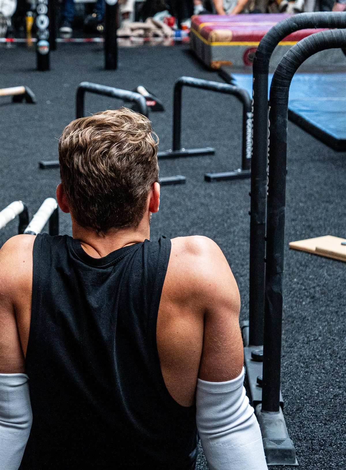 Sjakie Minet seen from behind, sitting between sets at a calisthenics competition