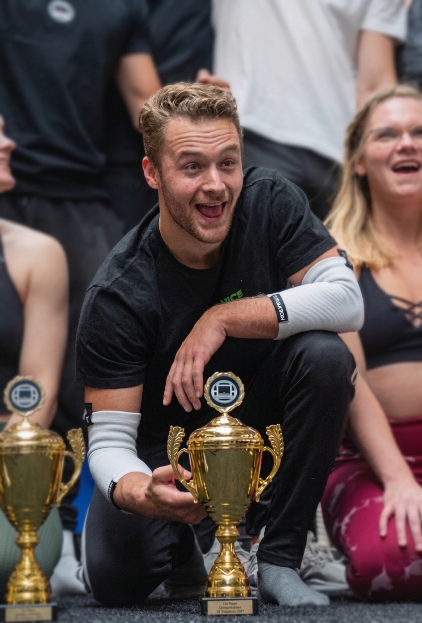 Sjakie Minet, Dutch calisthenics champion, kneeling beside his first place trophy