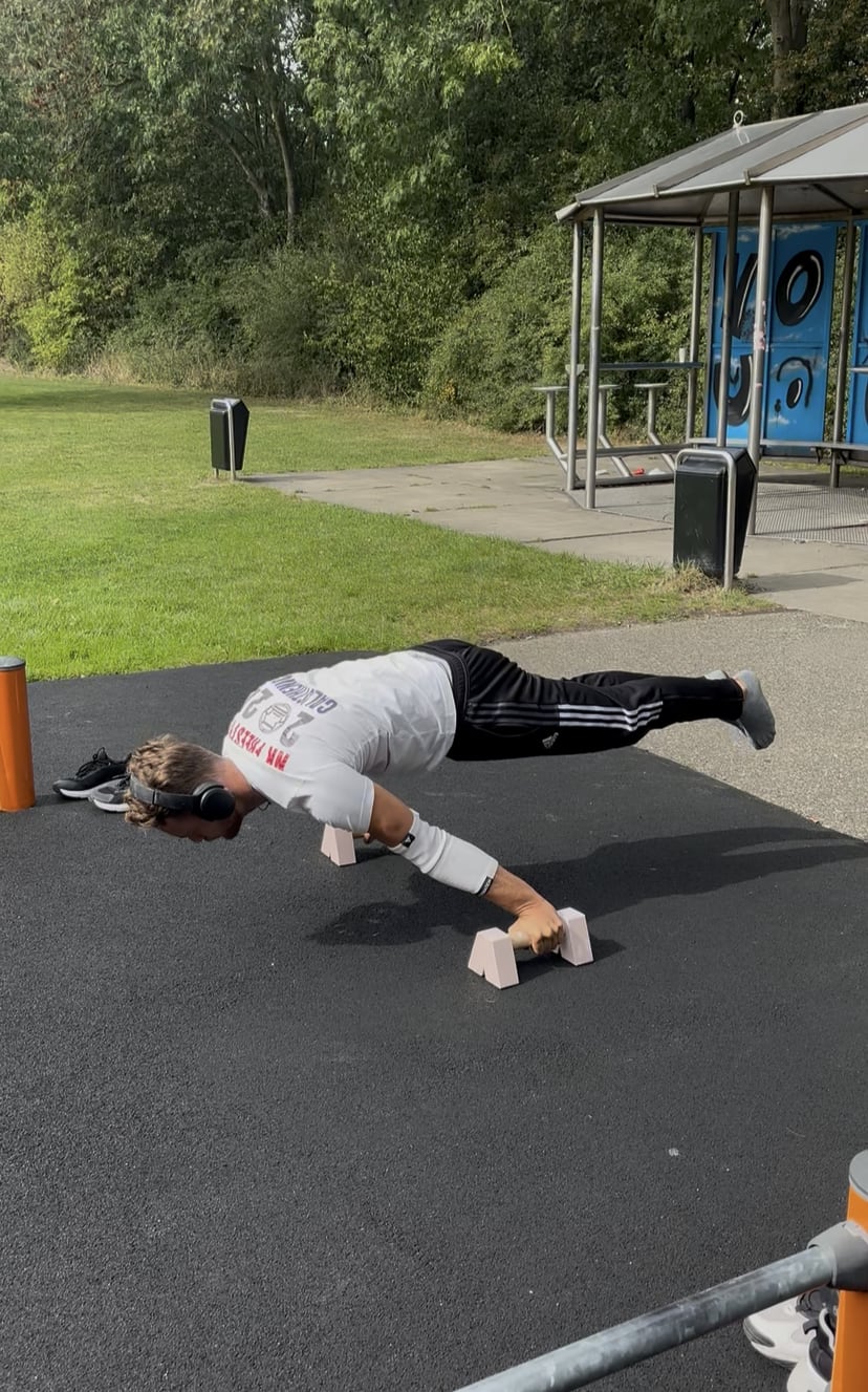 Sjakie Minet training the planche on parallettes in an outdoor calisthenics park