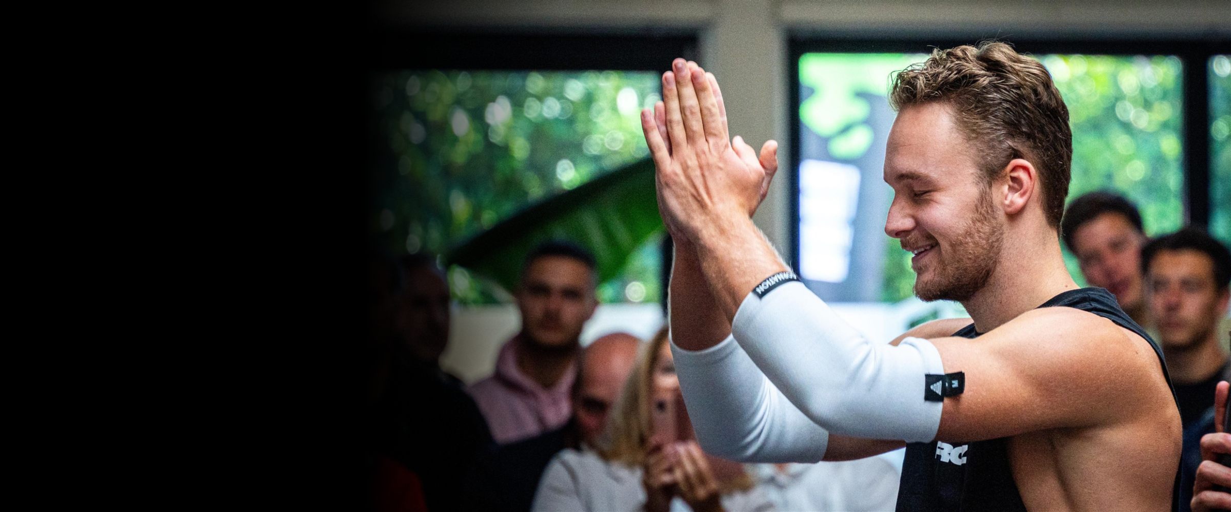 Sjakie Minet clapping after his routine at a calisthenics competition, crowd behind him